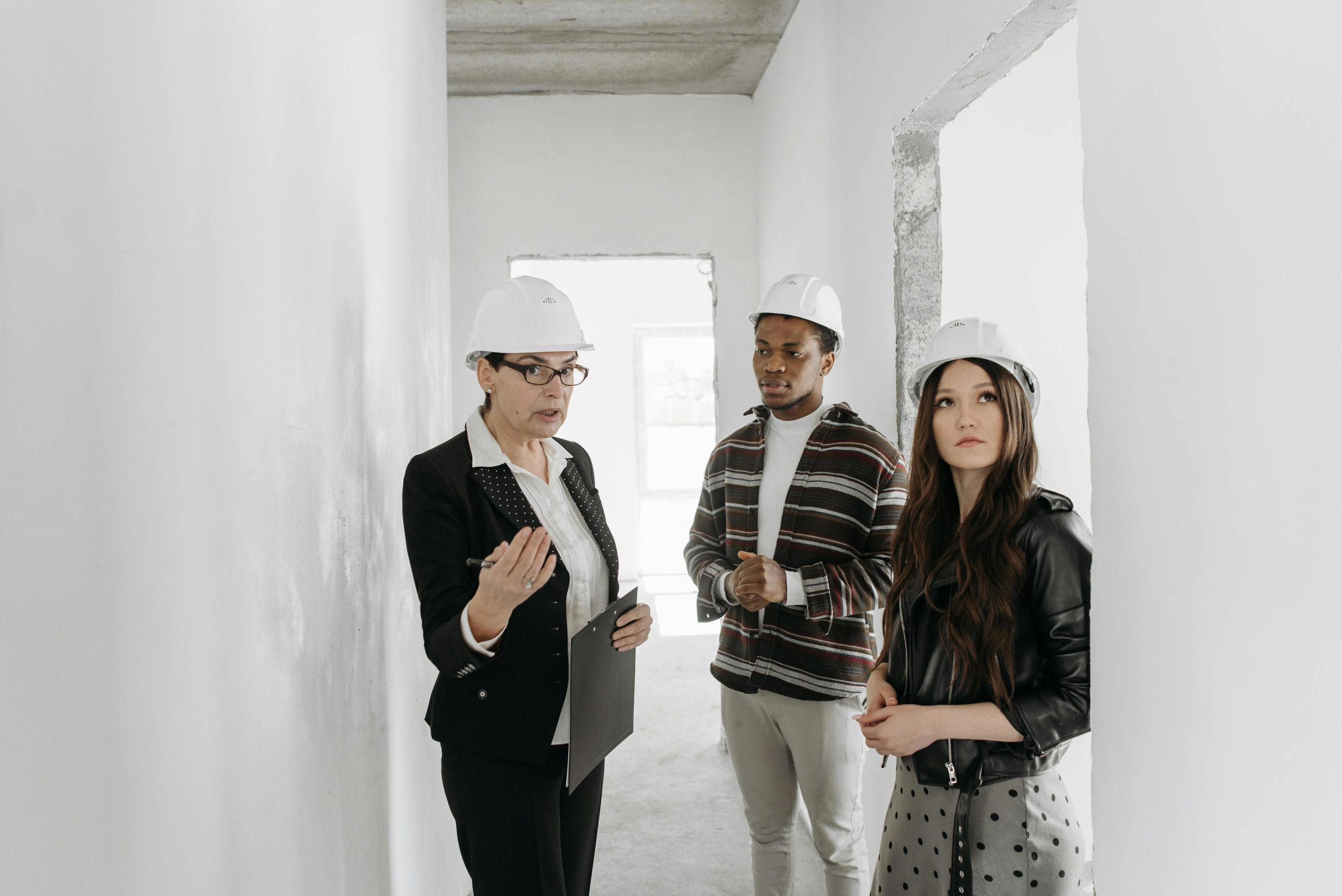 people wearing white hats looking to buy a house talking to a real estate agent